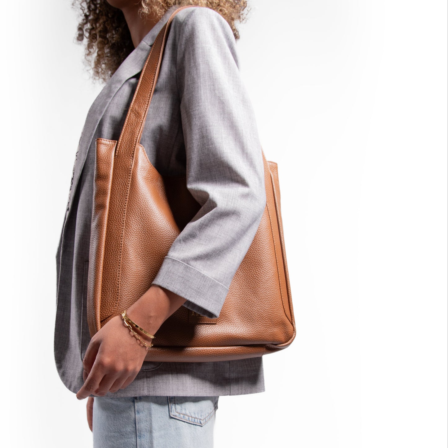 Person holding a brown leather laptop handbag against a white background