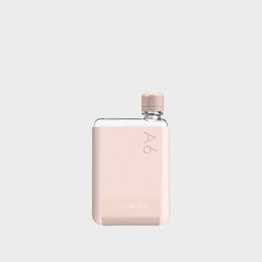 A pale coral colored A6 Memobottle with a stainless steel lid, designed to fit into handbags or pockets easily