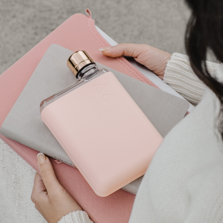 A pale coral colored A6 Memobottle with a stainless steel lid, designed to fit into handbags or pockets easily