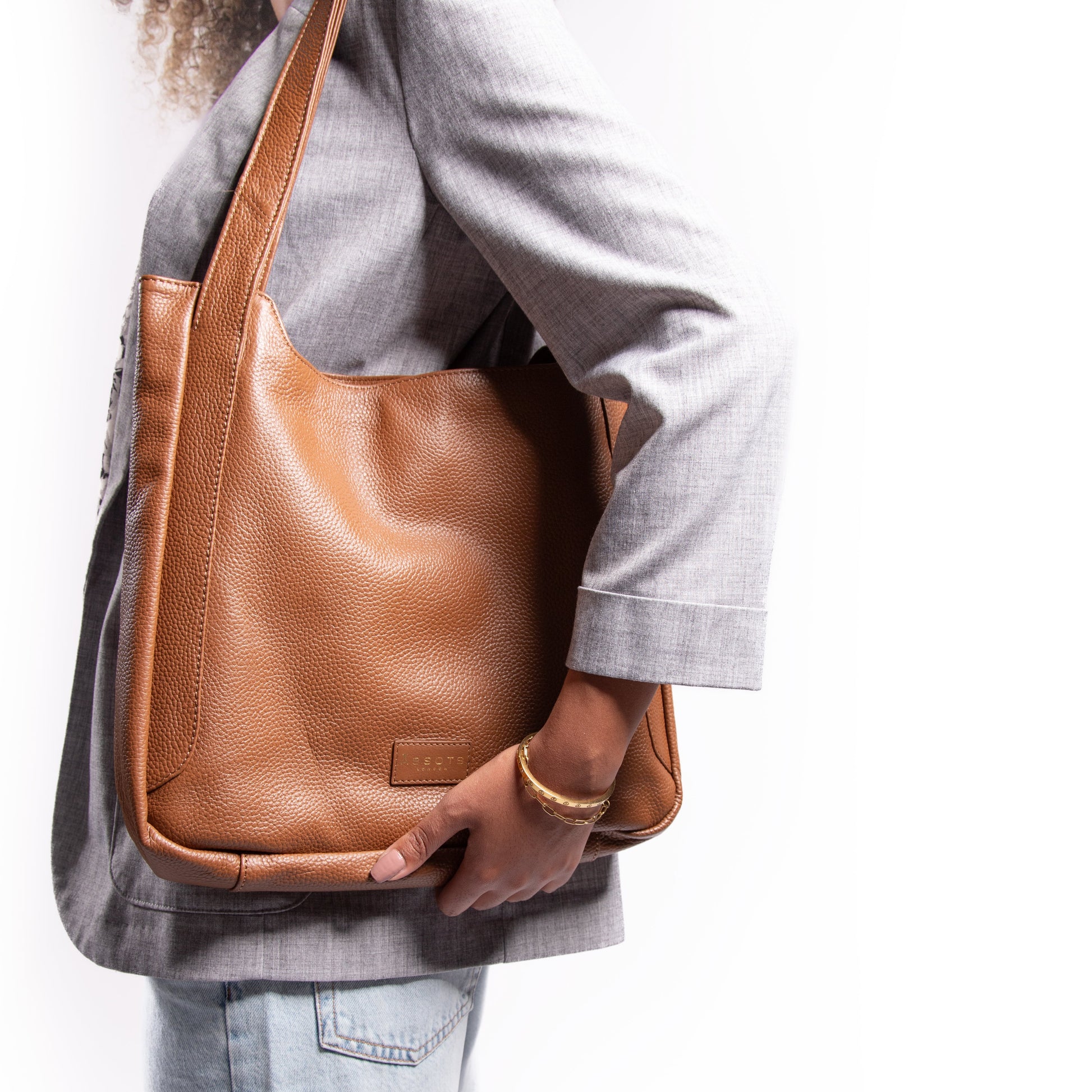 Woman holding a brown leather laptop handbag against a white background