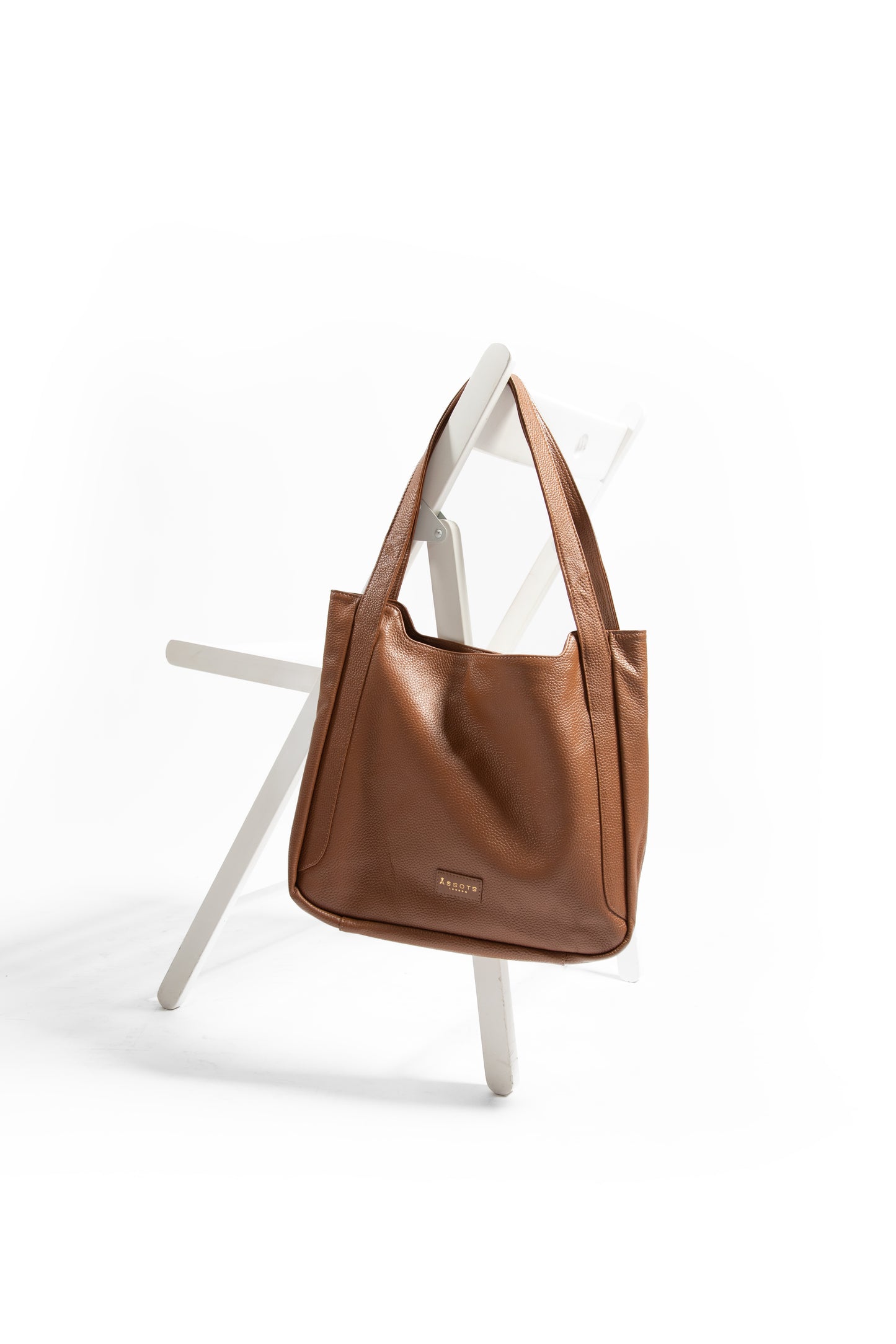 Brown leather laptop handbag on a white chair against a white background
