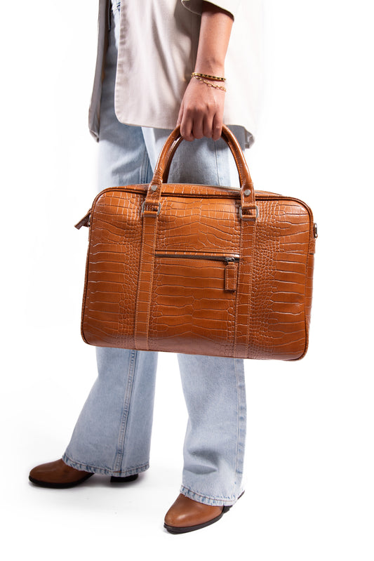 Person holding a brown leather laptop handbag against a white background